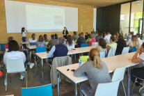 Personen sitzen an Tischen in einem Lehrsaal