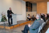 Frauen in Dirndln stehen an Stehtischen in Veranstaltungssaal
