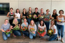 Gruppenbild der Studierenden, die Blumenstrauß oder Gesteck halten