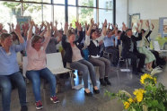 Teilnehmer in Veranstaltungssaal heben Hände in die Höhe.