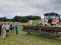 Personen stehen hinter Traktor mit Fräse