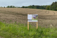 Acker, vor dem Tafel an Holzstelen angebracht ist