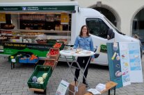Frau steht hinter Tisch nahe eines Marktstandes