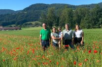 5 Personen stehen auf einer Wiese mit Mohnblumen