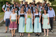 Personen in Dirndeln und Lederhosen stehen auf Treppe im Freien
