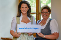 Michaela Kainber und Anneliese Göller halten Plakat mit Aufschrift www.bäuerin.bayern
